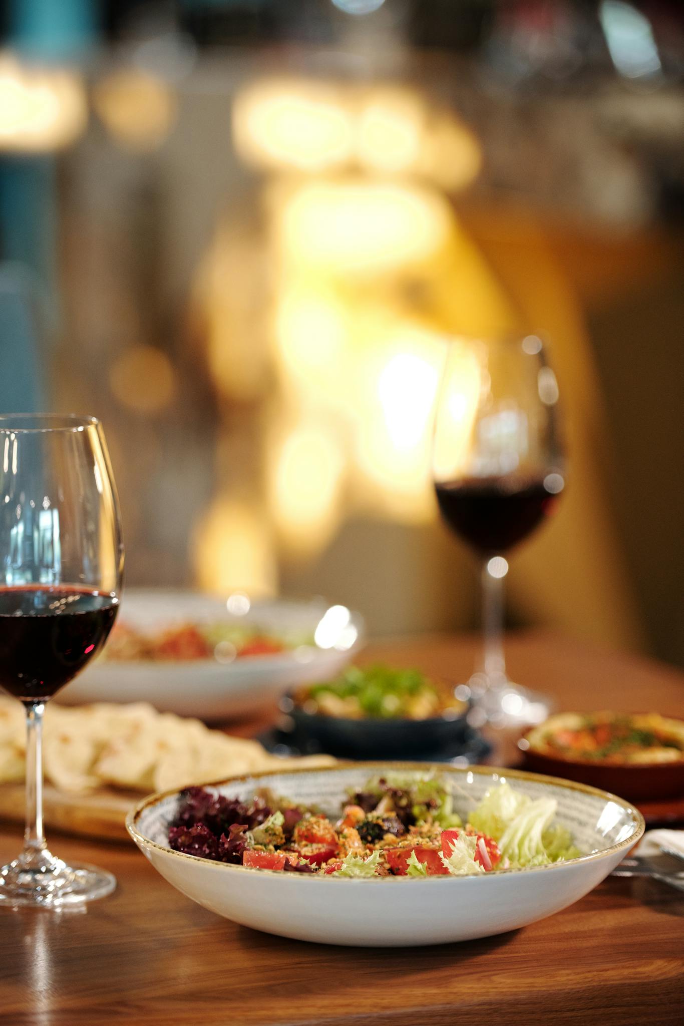 A beautifully arranged dinner table with salad and red wine, perfect for fine dining experiences.