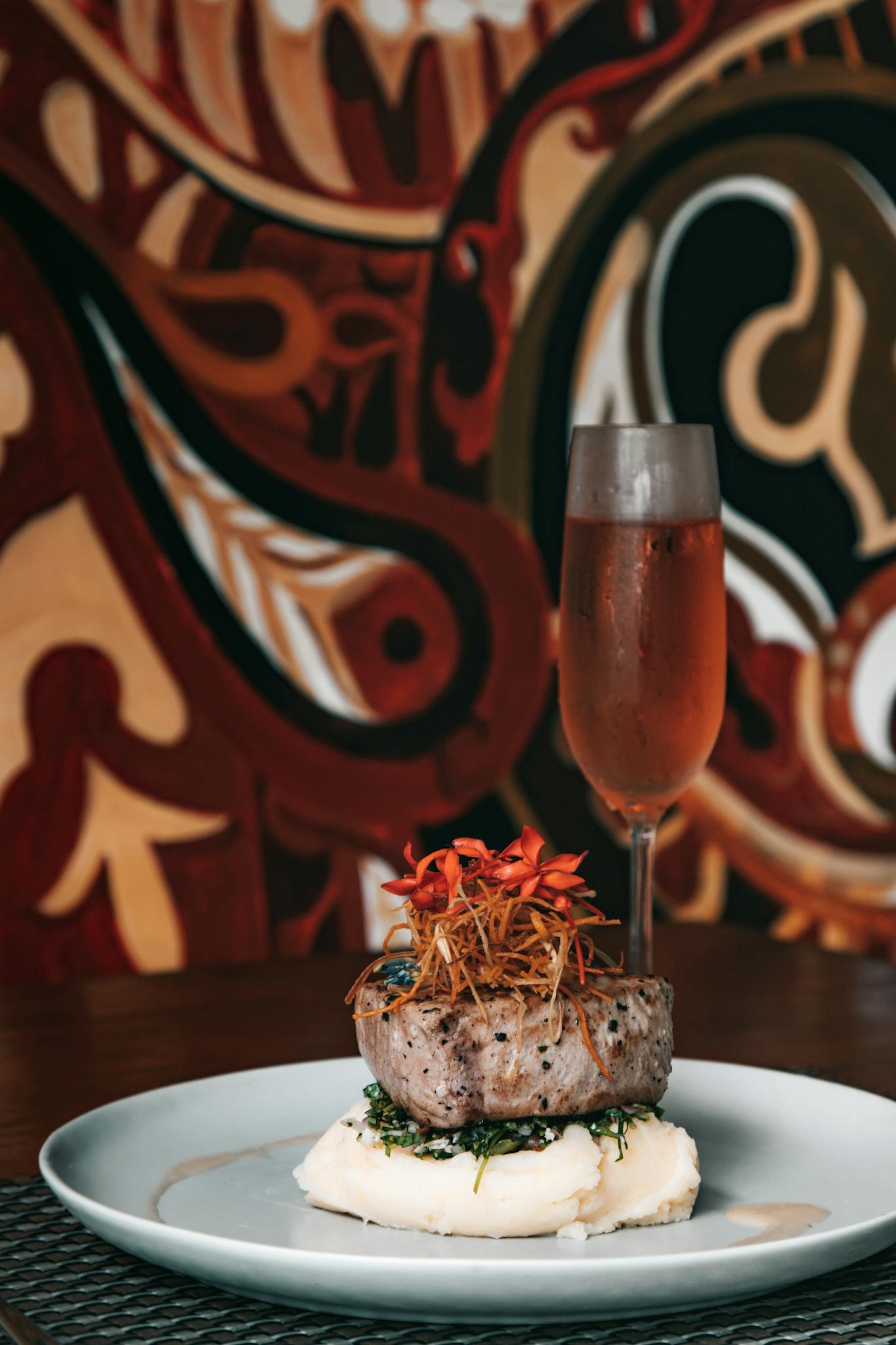 Elegant plating of gourmet food with champagne against a vibrant artistic backdrop.